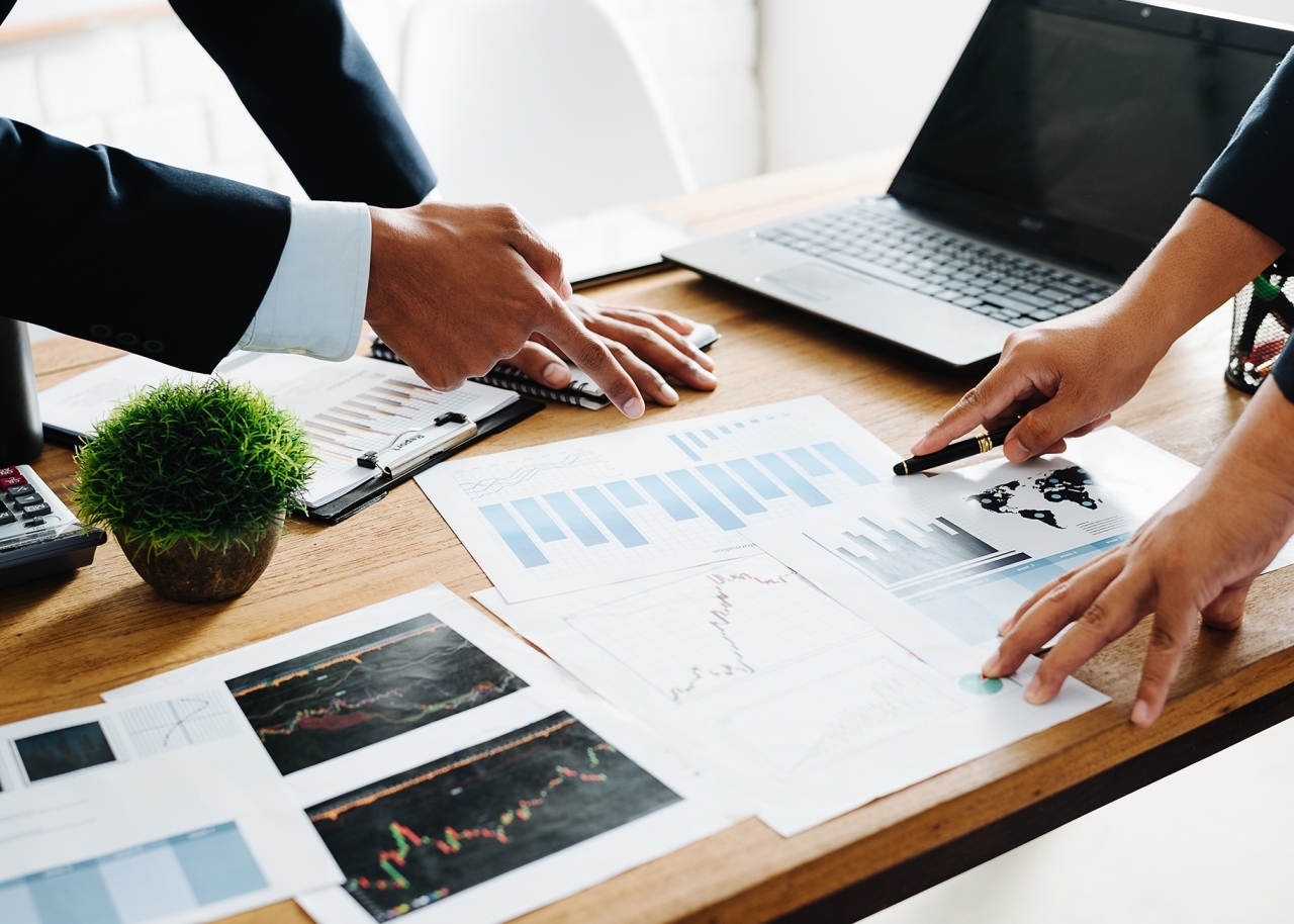 Closeup of professionals pointing at charts on desk